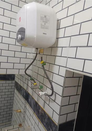 a white tiled bathroom with a light on the wall at Travel Lodge Apartment in Sagisa