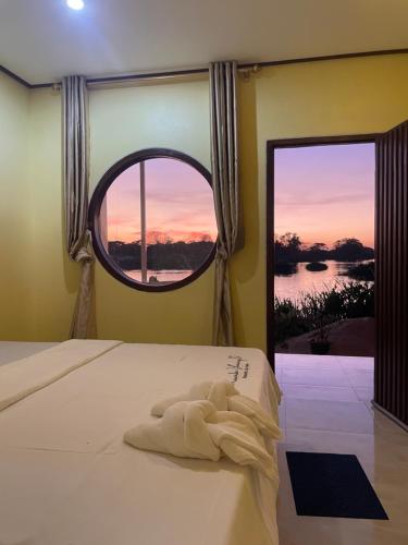 una camera da letto con un letto con una grande finestra di Tena Guest House a Don Det