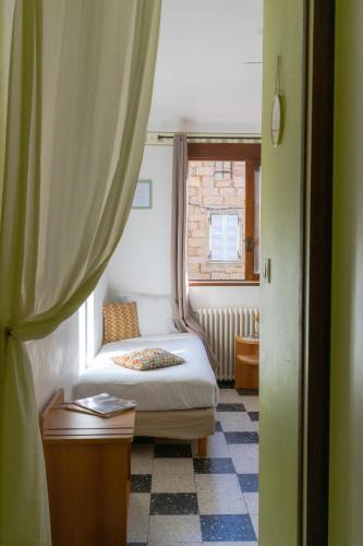 a small bedroom with a bed and a window at Hôtel Restaurant Sole e Monte in Cuttoli-Corticchiato