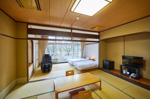 a room with a bedroom with a bed and a tv at Shiki Resorts Kusatsu Saisonnier in Kusatsu
