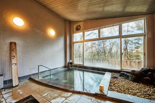 a hot tub in a room with a large window at Shiki Resorts Kusatsu Saisonnier in Kusatsu