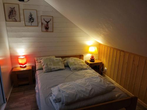 a bedroom with a bed with two lamps on two tables at le familial avec spa, sauna salle de jeux in Xonrupt-Longemer