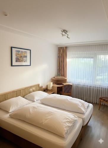 sypialnia z dwoma łóżkami, stołem i oknem w obiekcie Hotel Gästehaus am Kurpark w mieście Villingen-Schwenningen