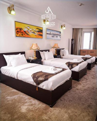 a hotel room with four beds and a chandelier at Al-Assadi Hotel in Erbil