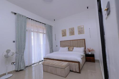 a bedroom with a bed and a chair and a window at Matanak 2 in Munyonyo