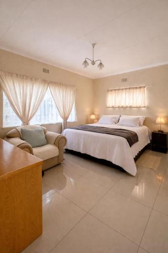 una grande camera da letto con un grande letto e un divano di Meadway on the parks a Benoni