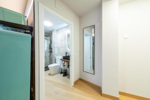 een gang met een spiegel en een badkamer met een toilet bij Apartamentos muralla de Lugo in Lugo