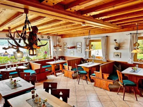 a restaurant with tables and chairs and a chandelier at Hotel Fischerstüberl am See in Tegernsee