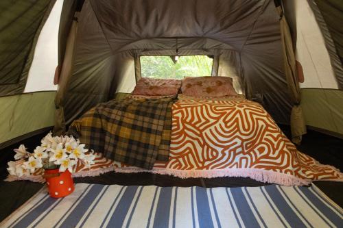 a bed in a tent with flowers in a vase at WA Wilderness Camping Experience in Pemberton