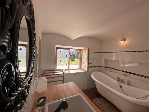 een badkamer met een bad, een wastafel en een spiegel bij Villa Le Chant du Tilleul in Le Poët-Laval