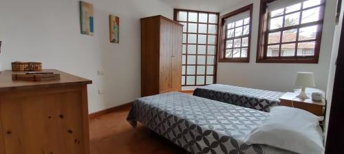 a bedroom with two beds and a table and two windows at Casa Magali in Tacoronte
