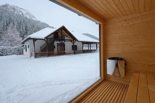 a window in a cabin with snow on the ground at Lacu Roșu Mountain Lodge in Lacu Rosu