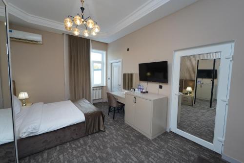 een slaapkamer met een bed, een bureau en een televisie bij Marison Hotel Baku in Baku