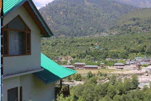 a house with a green roof with a mountain in the background at Maverick HomeStay in Baragrān