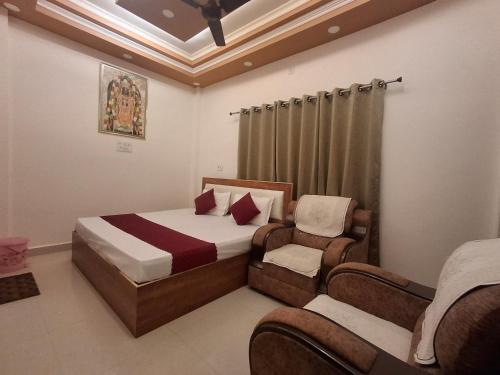 a bedroom with a bed and two chairs in it at Vamika Palace in Ayodhya