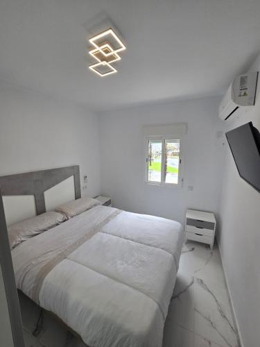 a white bedroom with a bed and a window at Bellavista in La Línea de la Concepción