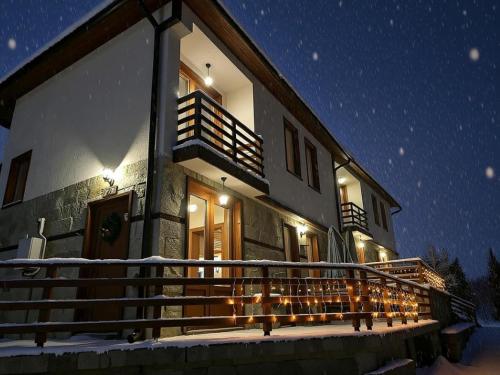 een huis met kerstverlichting op de veranda 's nachts bij Комплекс БОЖИДАРИЦА in Progled