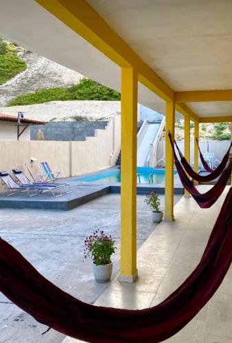 a hammock on a patio next to a pool at Pousada Dunnas do Thyago - preços de inauguração - Praia de Caraúbas - Vista para o mar e para as dunas in Maxaranguape