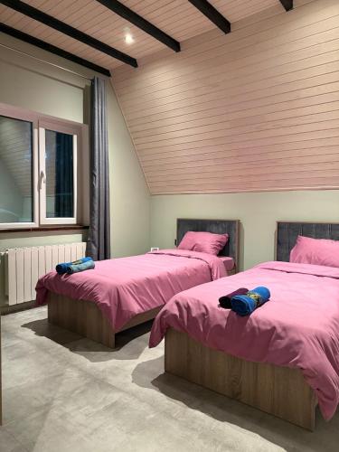 two beds in a room with pink sheets at SkyHouse Shahdag in Əniq