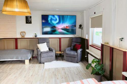 un soggiorno con due sedie, un letto e una TV di Gemütliche Ferienwohnung in Nordschweden a Glommersträsk