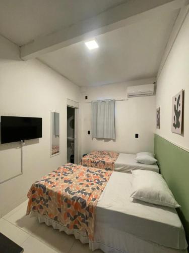 a bedroom with a bed and a flat screen tv at Ster Suítes in Maceió