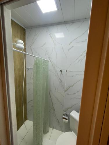 a bathroom with a shower and a white marble wall at Ster Suítes in Maceió