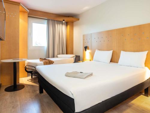 ein Hotelzimmer mit einem großen Bett und einem Stuhl in der Unterkunft Ibis Alcala de Henares La Garena in Alcalá de Henares