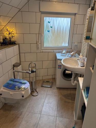 een badkamer met toilet, wastafel en raam bij Ferienwohnung Gartenblick in Nordenham