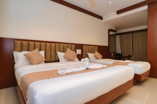 two beds in a hotel room with towels on them at Hotel Yathra Athithya in Dharmastala