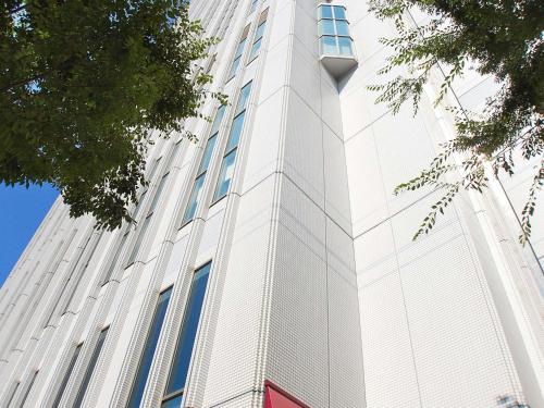 a tall white building with blue windows on it at Mercure Yokosuka in Yokosuka