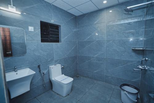 a bathroom with a toilet and a sink and a shower at Hotel Yathra Athithya in Dharmastala
