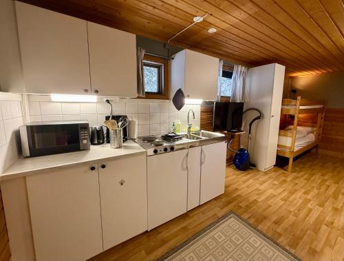 een keuken met witte kasten en een magnetron bij Kolbackens Camping & Stugby in Åsarna