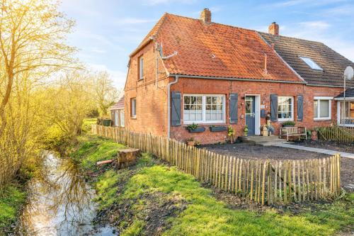 een stenen huis met een hek ervoor bij Huus an`t Dörpsdiek in Krummhörn