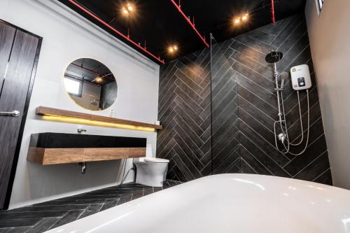 a bathroom with a tub and a sink and a mirror at The Brick Huahin Pool Villa in Hua Hin