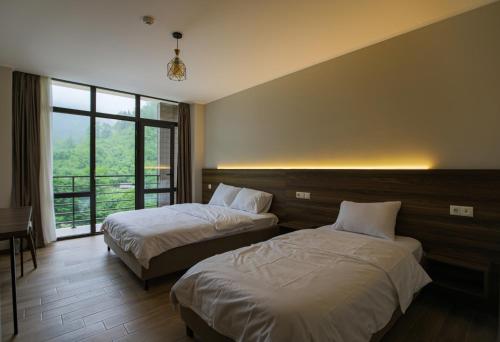 a bedroom with two beds and a large window at Nabada Hotel - Riverside in Ozurgetʼi