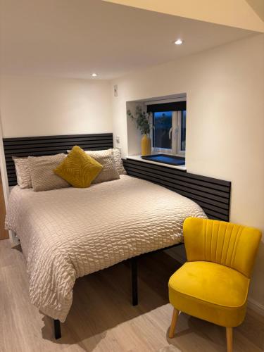 a bedroom with a bed and a yellow chair at The Cozy Forge in Horley