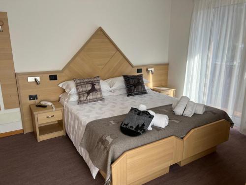 ein Schlafzimmer mit einem großen Bett mit einem hölzernen Kopfteil in der Unterkunft Hotel Ai Pini in Vigo di Fassa