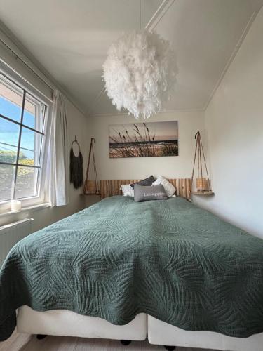 a bedroom with a large bed and a chandelier at Ferienhaus Breskens in Breskens