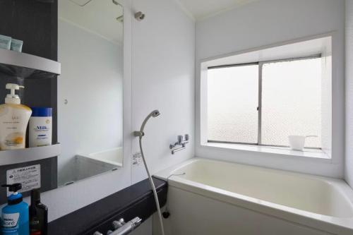 a bathroom with a bath tub and a window at Yamatsu Tokyo House in Tokyo