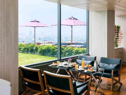 a dining room with a table and chairs and a large window at Mercure Bangkok Siam in Bangkok