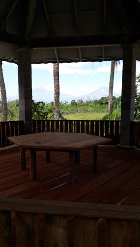 a wooden table on a deck with a view of a field at Griya Harja Homestay in Borobudur
