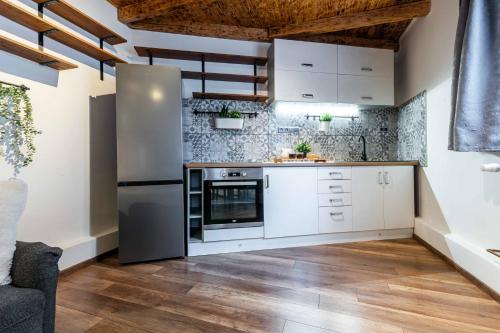 a kitchen with white cabinets and a stainless steel refrigerator at Apartmán U Hluboké studny in Rakovník
