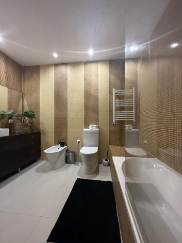a bathroom with a tub and a toilet and a sink at Luxury Modern Triplex Apartment in Póvoa de Varzim