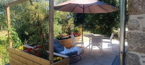 a patio with an umbrella and a table and chairs at le petit moulin de Kerloroc in Ploudalmézeau