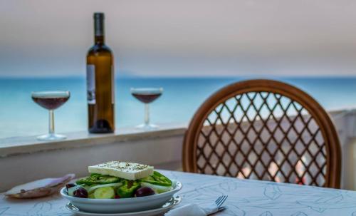 einen Tisch mit einem Teller Essen und einer Flasche Wein in der Unterkunft Villa Kostas in Vitalades