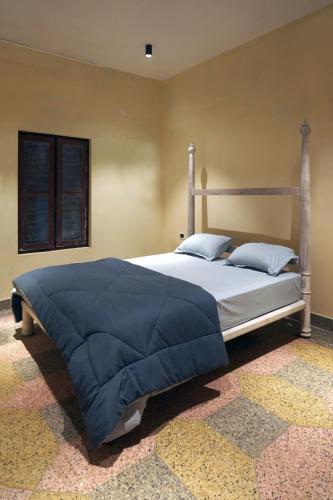 a bedroom with a large bed with blue sheets and pillows at Kash Beach Villa, Varkala - Steps from Odayam Beach in Varkala
