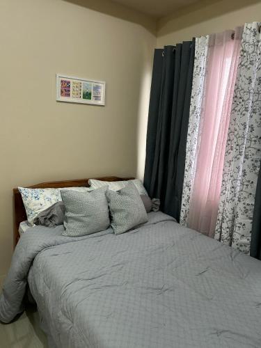 a bedroom with a bed with gray sheets and a window at Avida Tower 1, Unit 2003 - Chi's Place in Cagayan de Oro