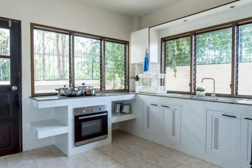 a kitchen with white cabinets and a sink and windows at Home to my heart mare pool villa in Jomtien Beach