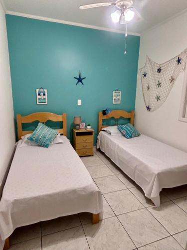 two beds in a room with blue walls at Casa Verde Bertioga, um espaço cheio de charme com três praias - Indaiá, Pedra Selada e Riviera de São Lourenço para visitar a pé! in Bertioga
