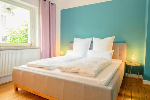 a bedroom with a bed with white sheets and a window at Hofgut Eveshausen - Dreiseitenhof - Spielscheune - Landidylle - Hofleben in Dommershausen